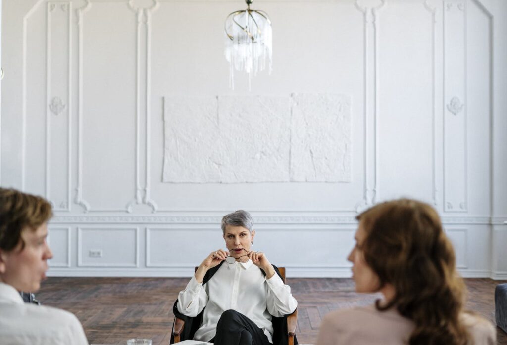 A therapist sits across from two clients during a therapy session.