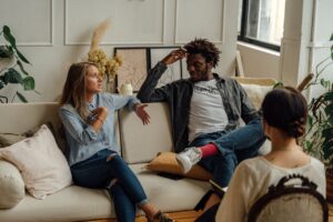 A couple speaks with a therapist during a counseling session in a warmly decorated office.